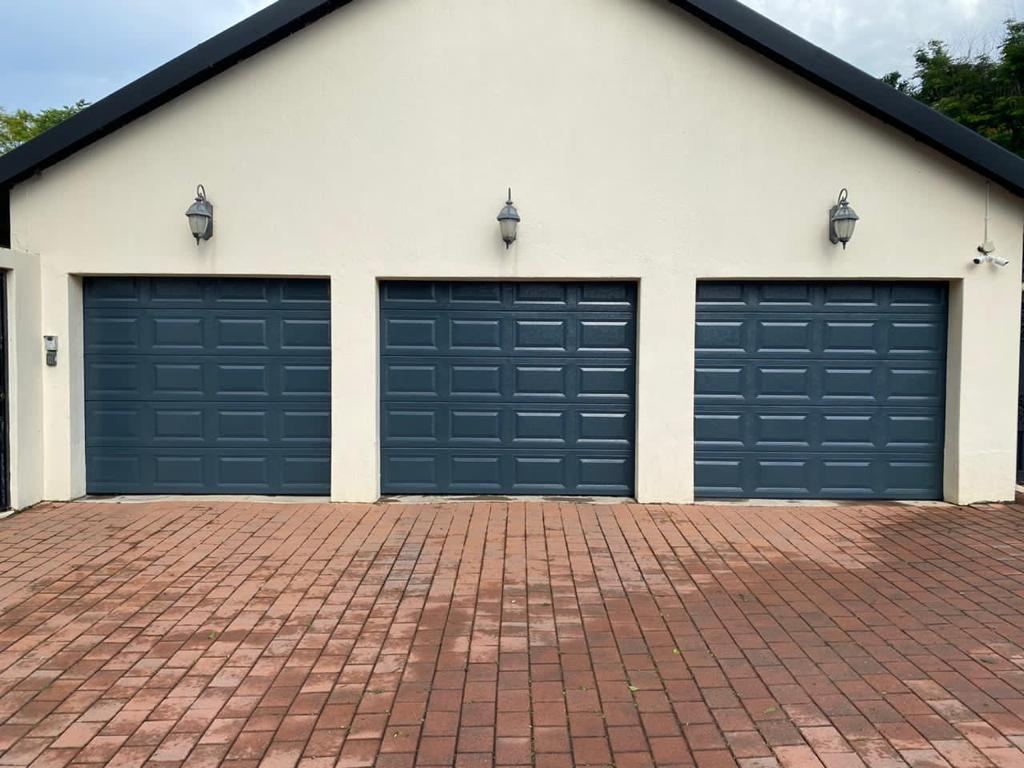 Three finished navy garage doors installed on an estate home